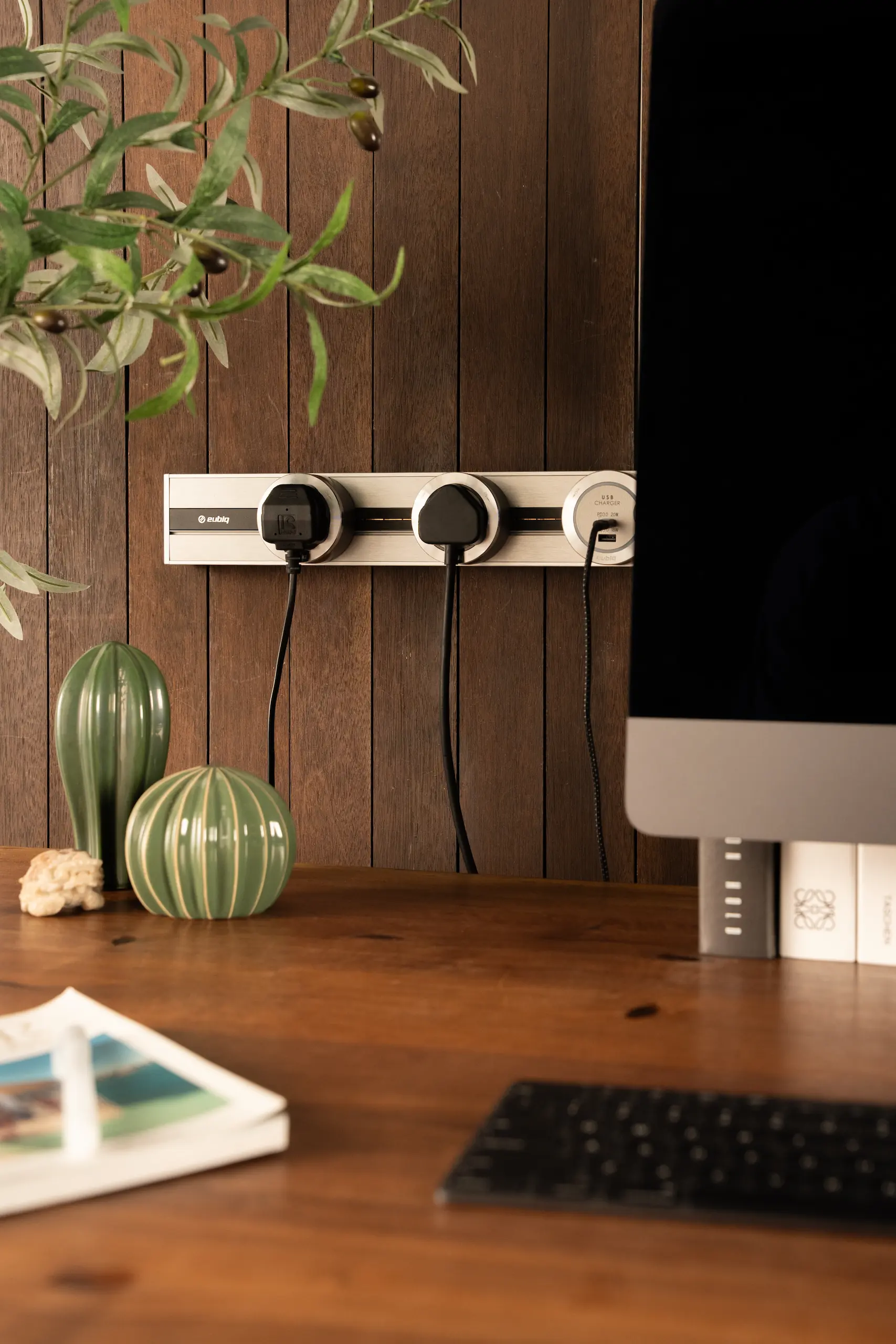 A workplace desk with Eubiq track and adapter mounted on the wall behind it, freeing up table space while keeping power accessible.